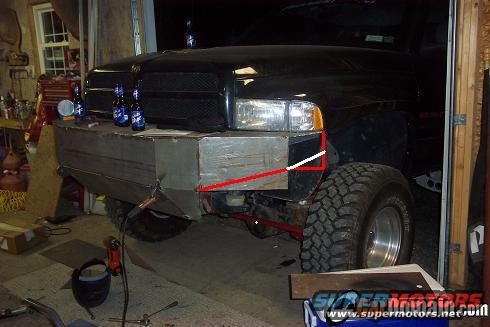 Truck with custom metal bumper being worked on in a garage. Beer bottles on top