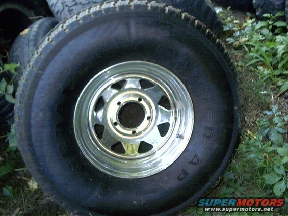 spare tire with a chrome rim, stacked with other tires outdoors