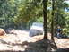 1988 Ford Bronco - White Ford Bronco tackles an off-road trail with a person watching nearby.