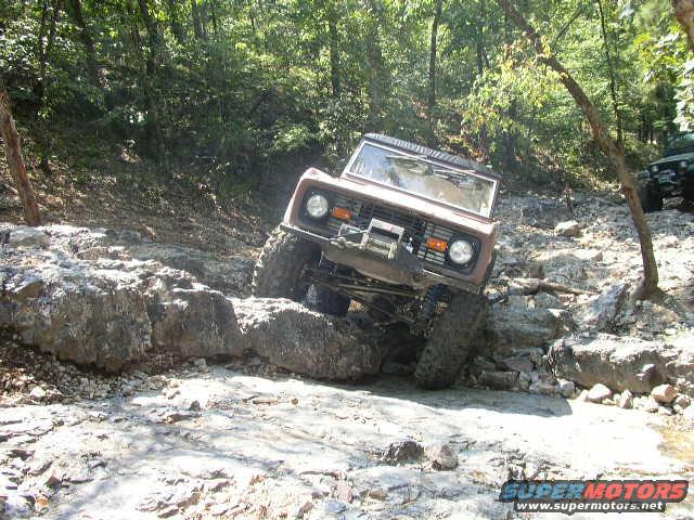 Brown Ford Bronco navigating rocky terrain, front-left 3/4 view, winch on bumper