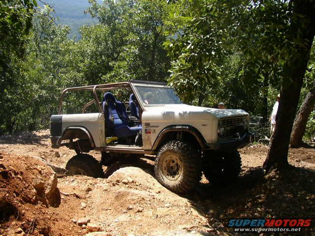 White 1970s Ford Bronco off-roading on a dirt trail