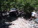 1988 Ford Bronco - A person watches a classic Ford Bronco navigate a challenging, rocky off-road path surrounded by dense foliage.