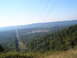 1988 Ford Bronco - A wide view of a forested valley with power lines cutting through it, under a bright sky.
