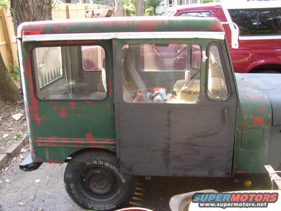 Jeep FC-150 with green and red paint, showing side door and windows. Red Ford Bronco in background
