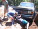 1988 Ford Bronco - A group of men attempt to free a stuck Ford truck from a ditch on a wooded trail.