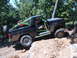 1988 Ford Bronco - Modified black Ford Bronco with a green roll cage navigates a rocky off-road trail.