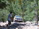 1988 Ford Bronco - A yellow SUV navigates a rocky, wooded trail with a person assisting.