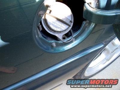 Close-up of a car's green fuel filler door and cap with warning text