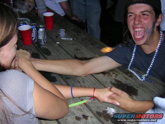 People arm wrestling at a picnic table with red cups and beer cans