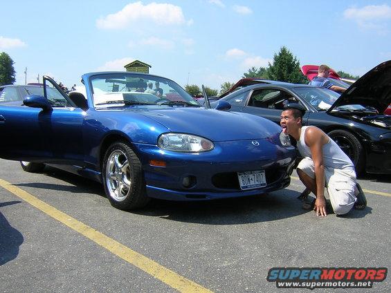 Blue Mazda Miata convertible with open door, man posing in front