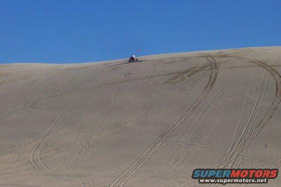 ATV on a sand dune with tire tracks