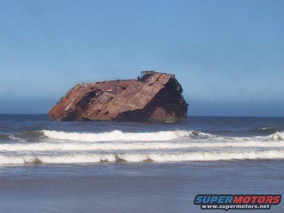 Wrecked ship on beach with waves crashing ashore