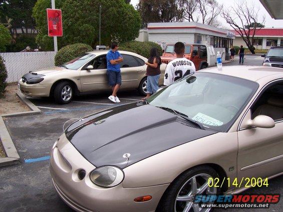 Gold sedan with black hood, parked next to an orange Jeep and another sedan