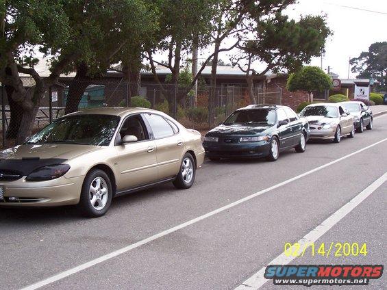 Four sedans parked in a line on a street, one with a car bra. Date stamp reads 02/14/2004