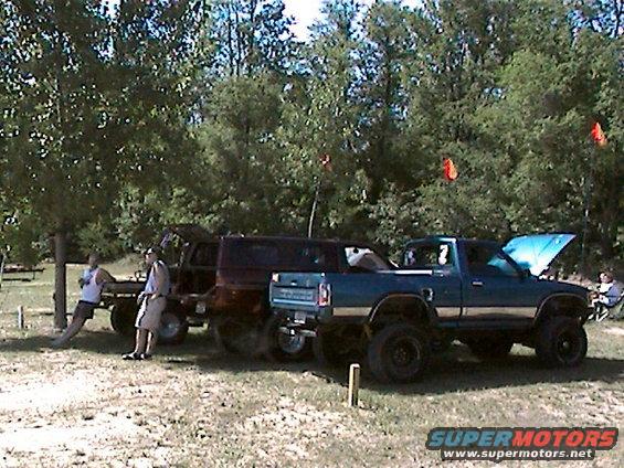 Blue pickup truck with lifted suspension and open hood, parked outdoors