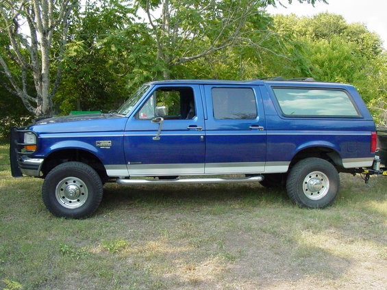 Blue extended cab pickup truck with camper shell, side view. Visible text: F-250