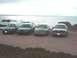 1995 Ford Taurus - Four 1995 Ford Taurus sedans are lined up on a sandy beach overlooking the ocean.