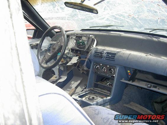 Interior of a car with dashboard removed, steering wheel visible, and broken windshield