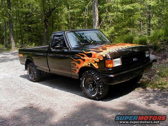 Black 1991 Ford F-150 with flame decals parked on a dirt road