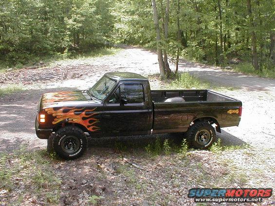 Black pickup truck with flame decals on the hood and fender, lifted suspension, and "4x4" decal on the bed