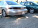 1995 Ford Taurus - Rear view of a gold sedan with dual exhaust pipes and aftermarket wheels, parked next to a green sedan.