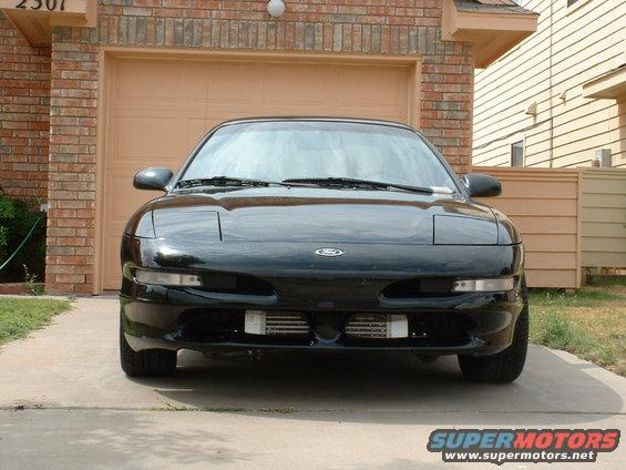 Front view of a black sports coupe with pop-up headlights and an intercooler visible behind the front bumper