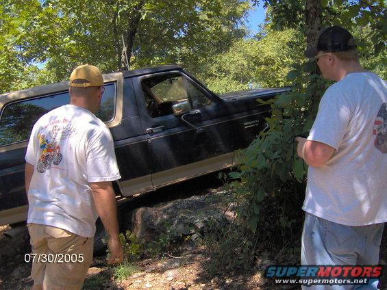Black 1978 Ford Bronco off-roading with two men observing