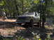 1978 Ford Bronco - A 1978 Ford Bronco navigates a wooded trail with a person standing nearby.