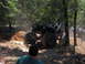 1978 Ford Bronco - A heavily modified Jeep navigates a challenging off-road course surrounded by trees.