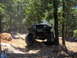 1978 Ford Bronco - A modified Jeep Wrangler YJ navigates a challenging off-road trail surrounded by trees.