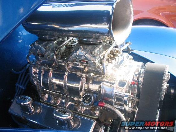Close-up of a chrome supercharger on a V8 engine with dual carburetors