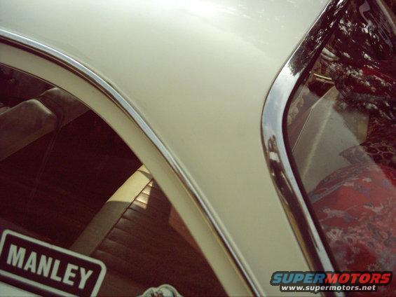 Cream-colored car roofline and interior with brown seats and a "MANLEY" sticker on the window