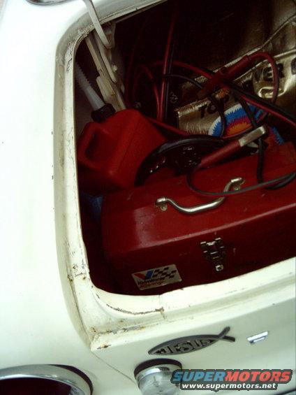 Trunk interior with red toolbox and gas can. 1962 Ford Falcon badge visible