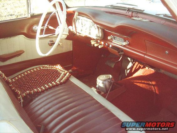 1962 Ford Falcon interior with red seats, white steering wheel, and dashboard