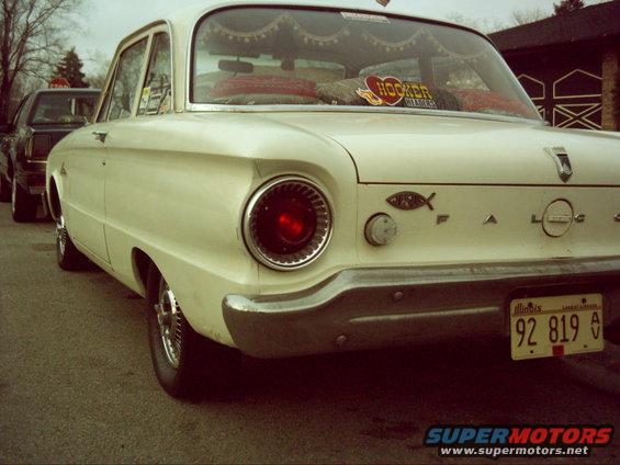 Cream-colored Ford Falcon sedan, rear view, with a red taillight and 'FALCON' badging