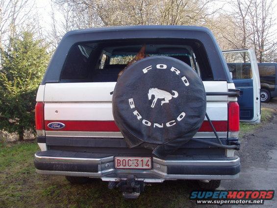 1988 Ford Bronco rear view showing spare tire cover with Bronco logo and license plate BOC-314. Another vehicle is parked to the right