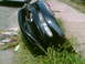 1997 Ford Probe - A damaged black car bumper with a headlight is discarded by the roadside.
