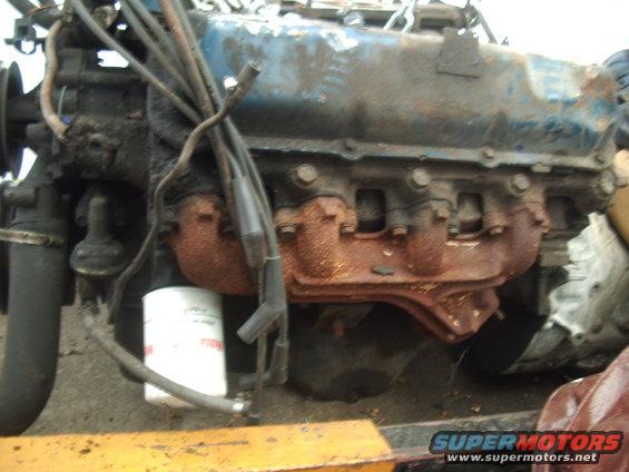 Engine with blue valve covers, rusty exhaust manifolds, and an oil filter