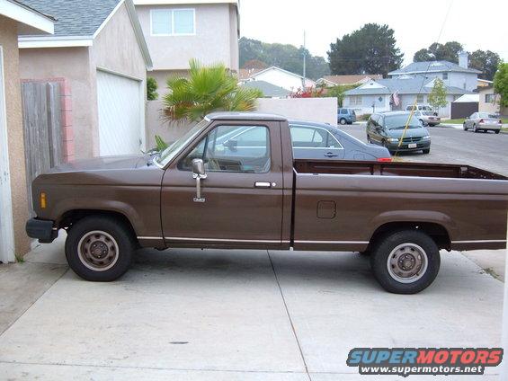 Brown pickup truck parked on concrete driveway, side view. Chrome trim along the bottom