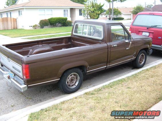 1985 Ford Ranger pickup truck, brown, parked next to a red van
