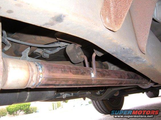 Underside view of a vehicle's exhaust pipe with visible weld marks