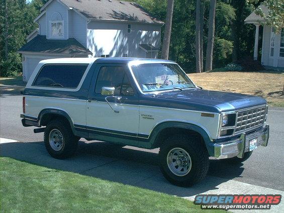 Two-tone blue and white Ford Bronco parked in front of a house
