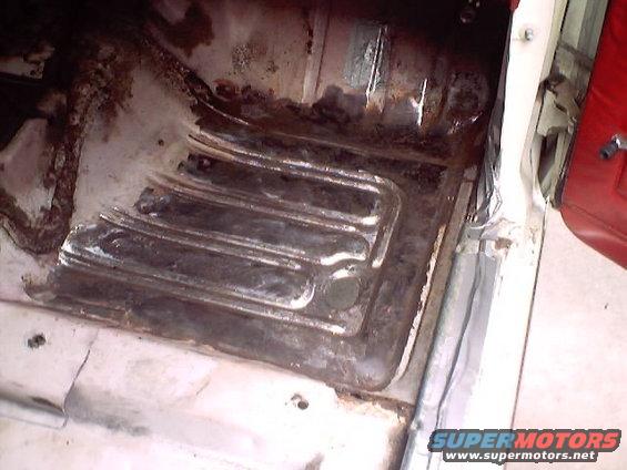 Interior shot of a rusty vehicle floor pan with ribbed metal sections