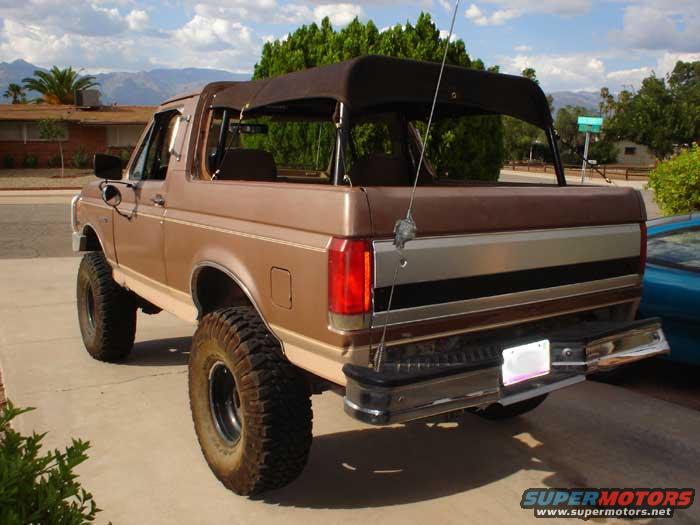 Brown soft-top SUV, rear view. Lifted with large tires