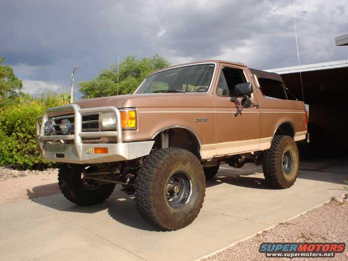 Brown Ford Bronco with aftermarket bumper and large tires parked on a driveway