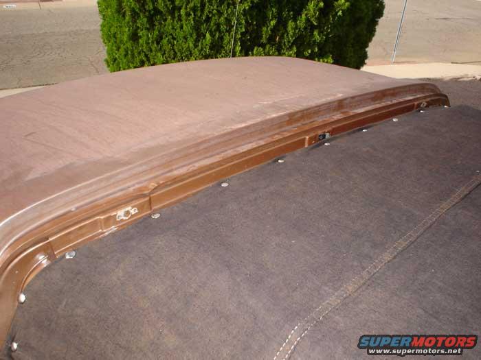 Brown car roof with visible seams and fasteners, next to a dark fabric top