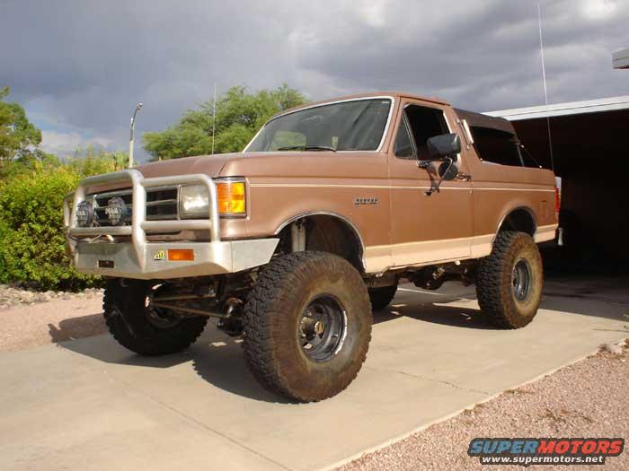 1989 Ford Bronco with large tires and brush guard parked on a driveway