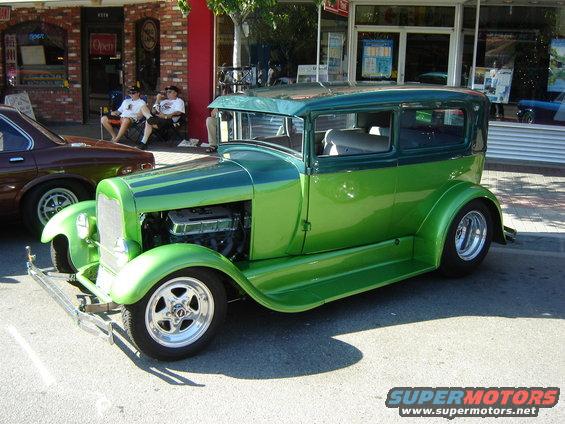 Two-tone green sedan hot rod with exposed engine, custom wheels, and lowered suspension