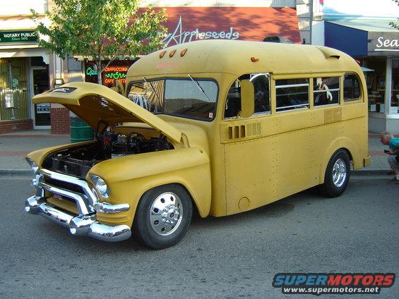 Yellow school bus conversion, front 3/4 view, hood open revealing engine