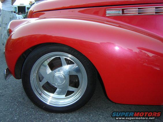 Close-up of a red classic car's front fender and custom five-spoke wheel